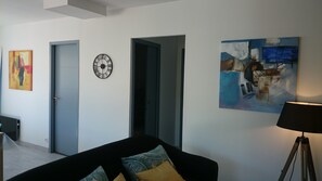 Ein modernes Wohnzimmer mit einem schwarzen Sofa, einer Uhr und abstrakter Kunst an den Wänden.