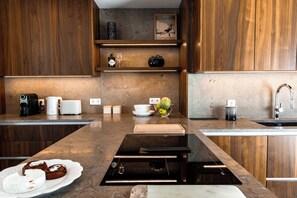 Een moderne keuken met houten kastjes, een ingebouwde oven, een koffieapparaat en een fruitschaal op het aanrecht.