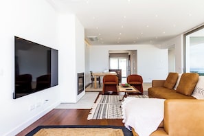 Ein modernes Wohnzimmer mit Flachbildfernseher, einer Couch und einem Essbereich mit Stühlen und Tisch.