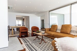 Een moderne woonkamer met een bank, twee fauteuils, een salontafel en een kamerbreed tapijt met een patroon.
