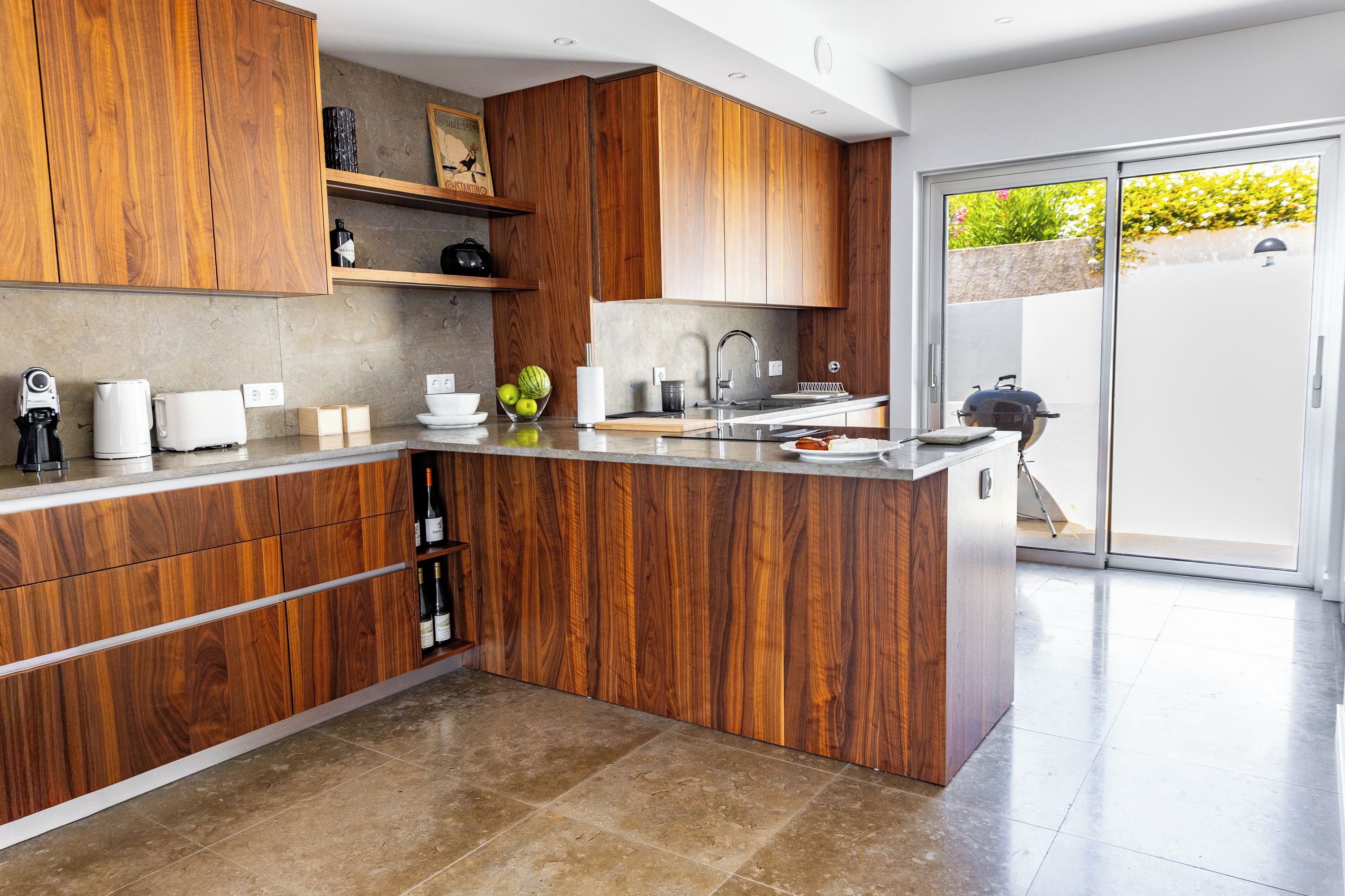 Una cocina moderna con armarios de madera, una isla integrada y un ventanal con vistas a un jardín.