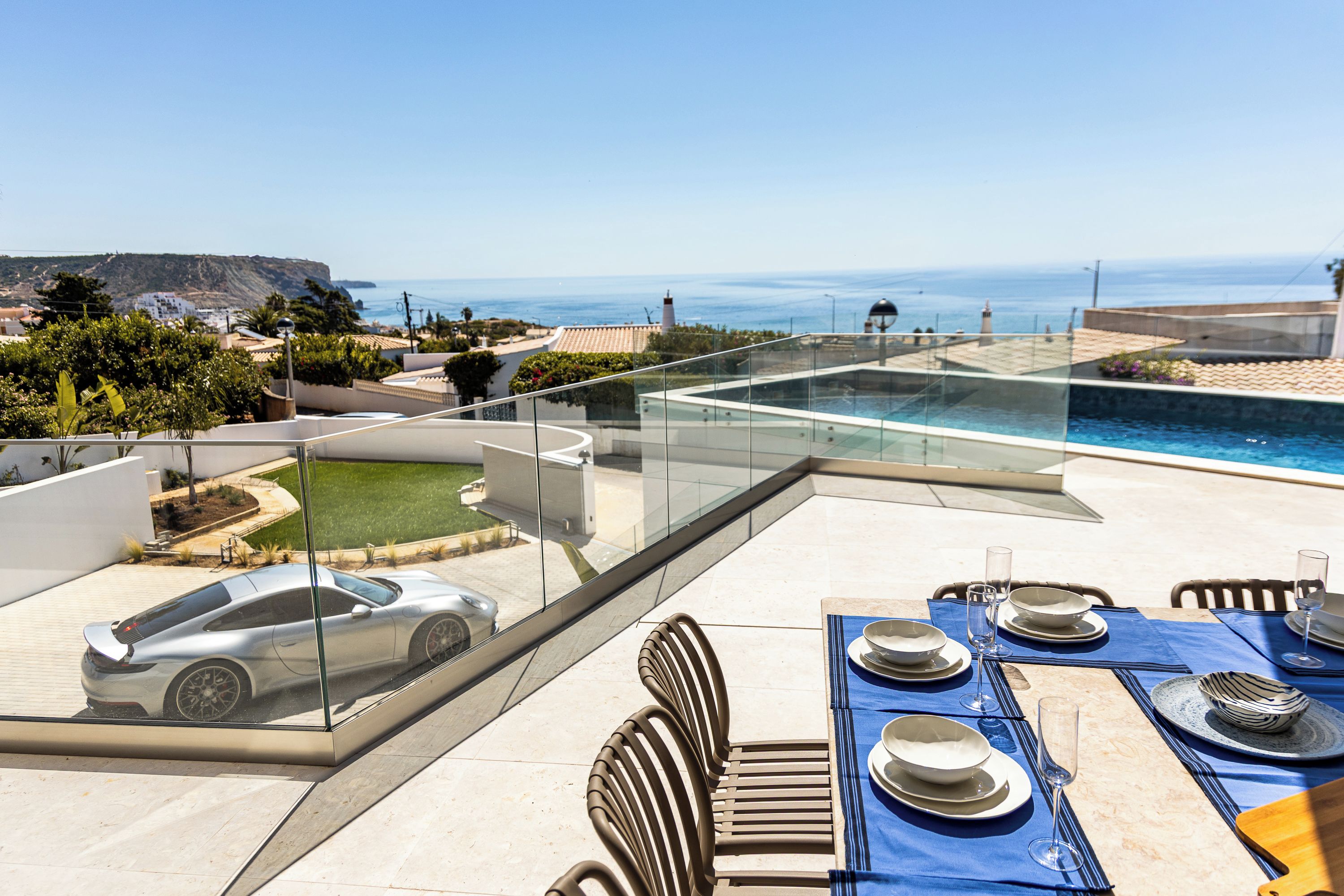 A rooftop terrace with a pool, dining setup, and a parked car.