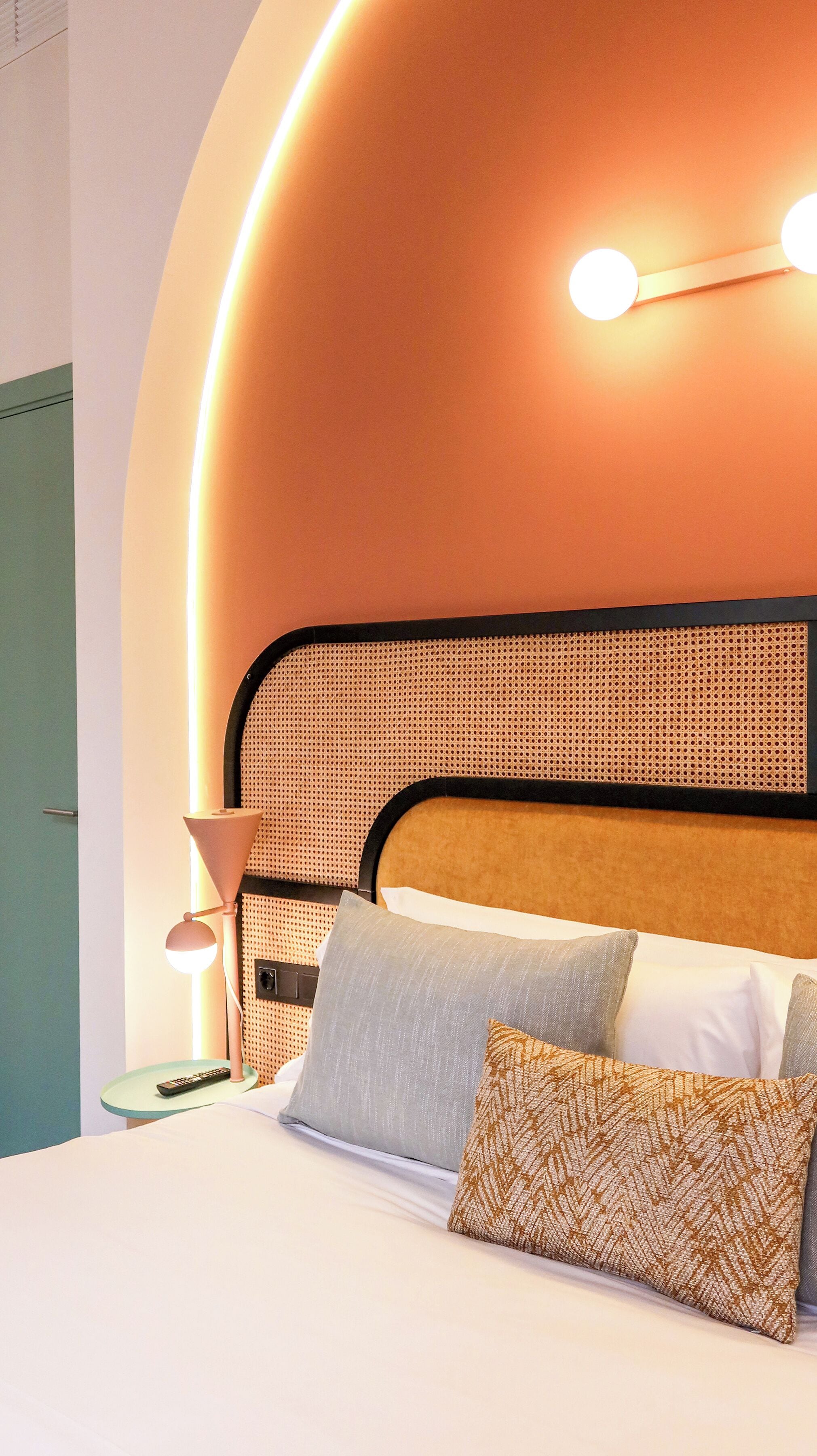 Una cama con cabecera, almohadas y una lámpara de noche.