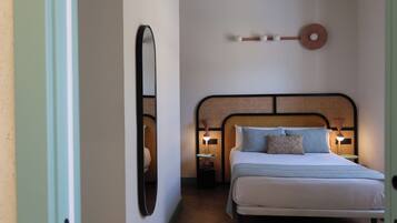 Un dormitorio con cama, lámparas de noche, un llavero en la pared y un espejo.