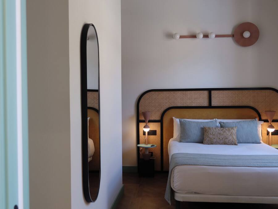 Un dormitorio con cama, lámparas de noche, un llavero en la pared y un espejo.