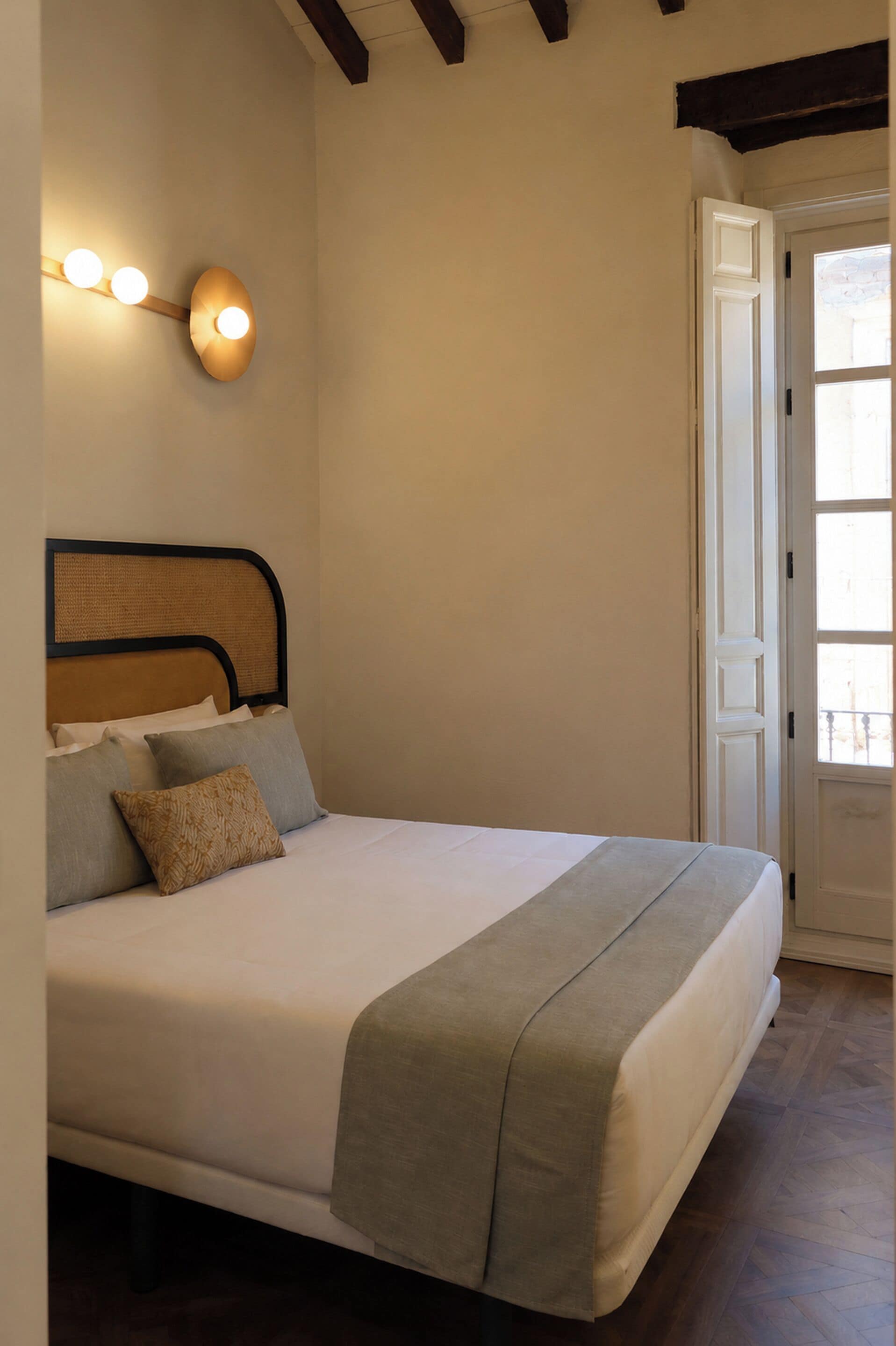 Un dormitorio con una cama, una lámpara de pared y una puerta.