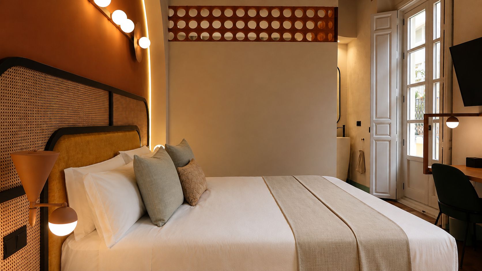 A neatly made bed with pillows, a bedside lamp, and a wall-mounted light fixture.