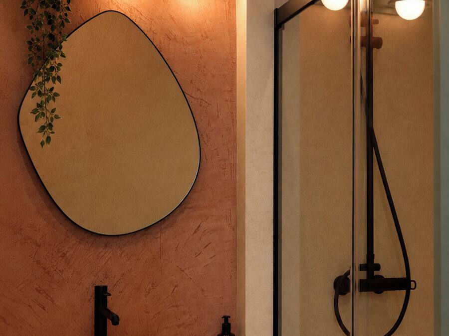 Un baño con un espejo redondo, un lavabo y una ducha.