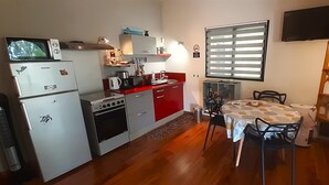 Cozinha compacta com área de refeições, equipada com micro-ondas, forno e geladeira.