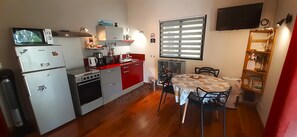 Een functionele keuken met een eethoek, voorzien van een magnetron, oven en koelkast.