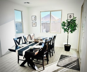 A dining area with a long table, chairs, and a potted plant. - Spacious 5-bedroom house in marvelous Maricopa with AC (Maricopa)