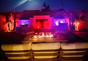 An outdoor patio with a fire feature, seating, and a stone wall backdrop. - Spacious 5-bedroom house in marvelous Maricopa with AC (Maricopa)