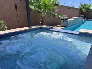 A hot tub with a stone border and a palm tree in the background. - Spacious 5-bedroom house in marvelous Maricopa with AC (Maricopa)