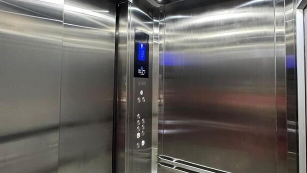 An elevator interior with a digital display and metallic walls.