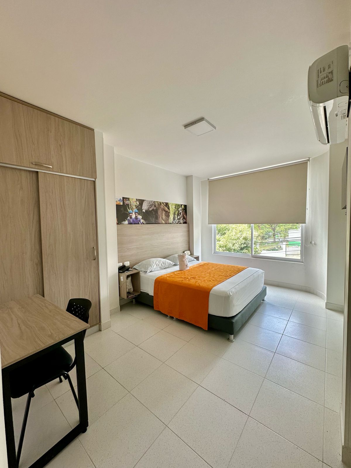 A hotel room with a bed, a desk, a wardrobe, and a window with a view.