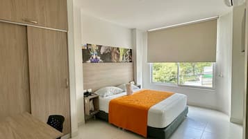 A hotel room with a bed, a desk, a wardrobe, and a window with a view.
