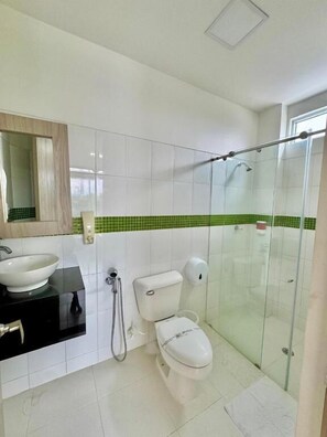 Une salle de bain avec un lavabo blanc, des toilettes et une cabine de douche en verre.