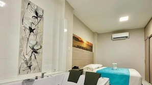 Ein modernes Badezimmer mit einer großen Badewanne, einer Dusche und einem Bett mit blauer und weißer Bettdecke.