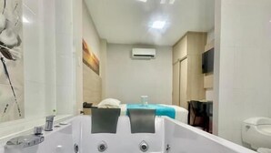 A modern bathroom with a large bathtub, a toilet, and a shower area.