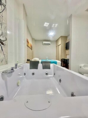 Un baño moderno con una bañera grande, inodoro y zona de ducha.