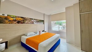 Ein Hotelzimmer mit Bett, Fenster, Kleiderschrank und einem Wandbild.