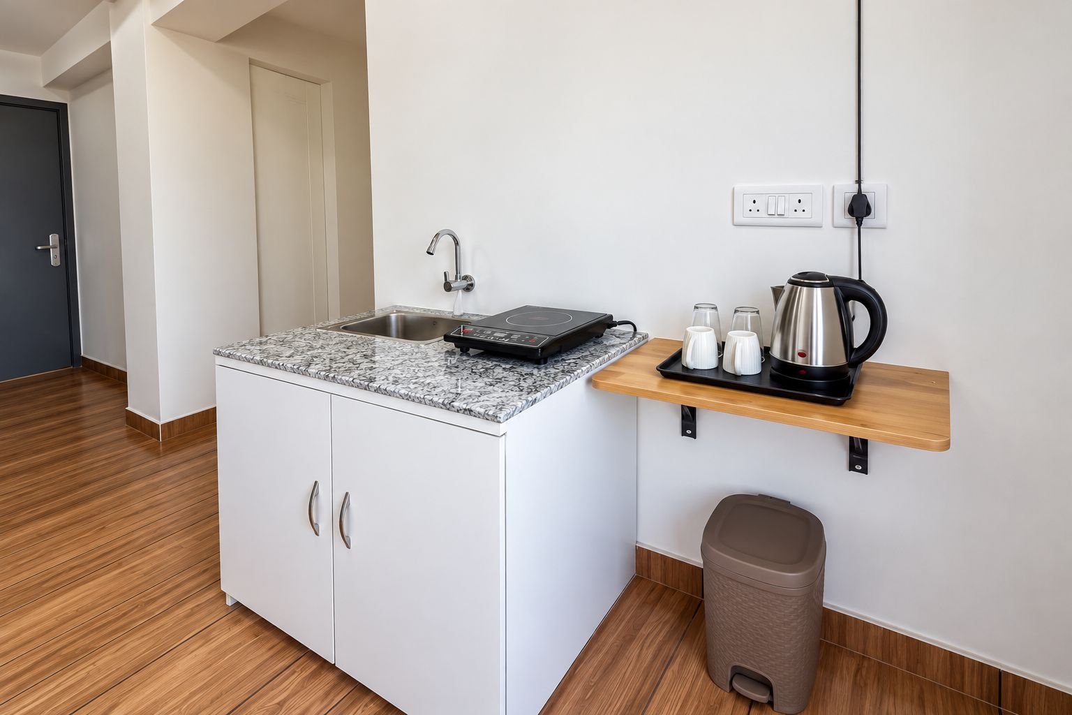 Una kitchenette compacta con estufa integrada, un lavamanos y una pequeña encimera.