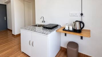 Una kitchenette compacta con estufa integrada, un lavamanos y una pequeña encimera.
