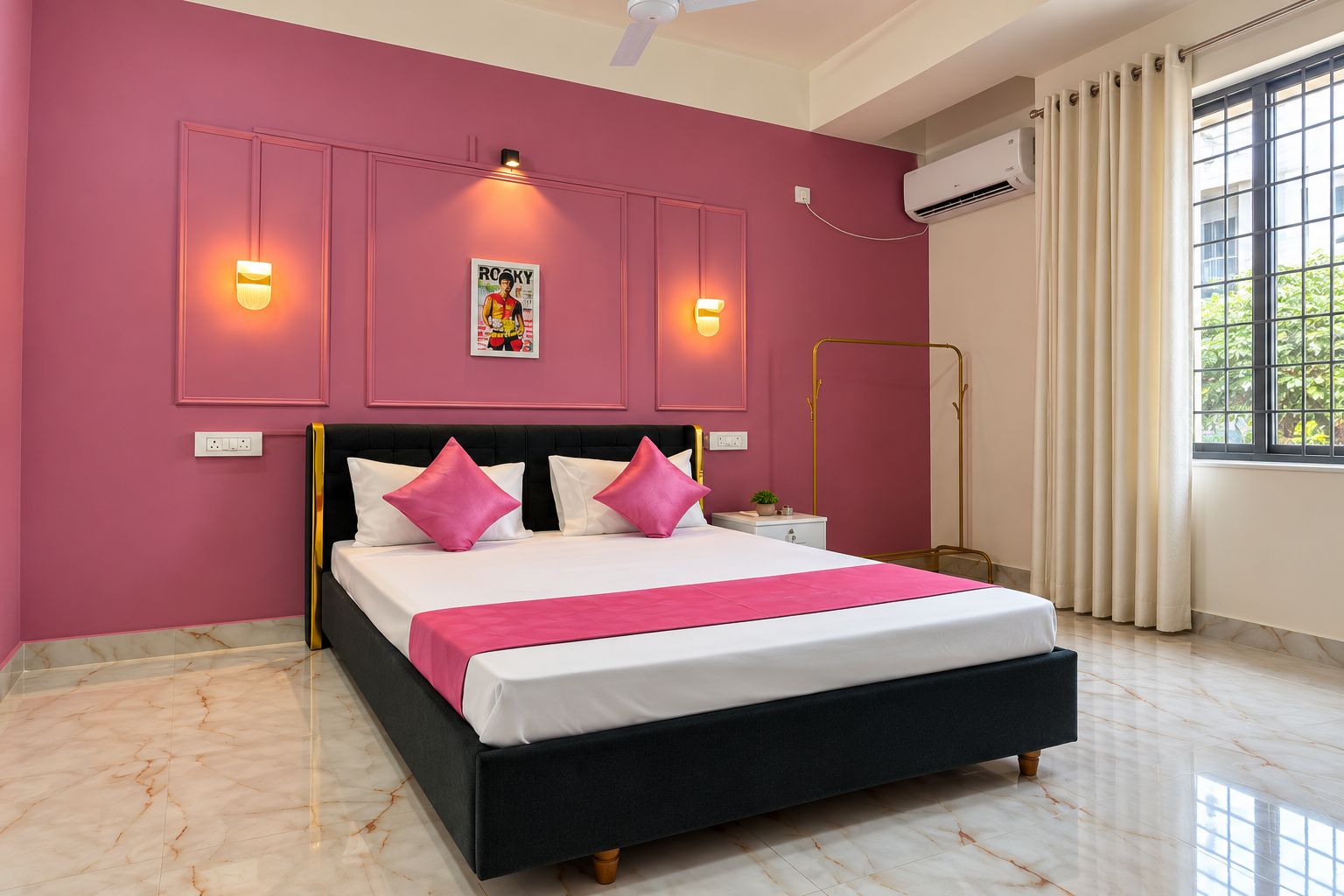 Quarto com cama, luminárias de cabeceira, um pôster, ar condicionado e janela com cortinas.