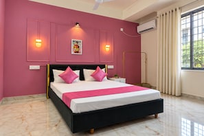 A bedroom with a bed, bedside lamps, a poster, an air conditioning unit, and a window with curtains.
