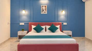 A bedroom with a bed, two bedside tables, a nightstand, a wall-mounted air conditioner, and a framed picture above the bed.