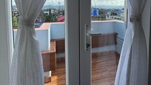 A balcony with a wooden floor and a view of a cityscape. - Beau Monde Suites (Guwahati)