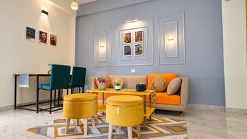 A modern living room with a sofa, two chairs, a table, and a patterned rug.