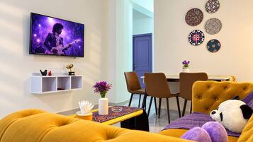 A modern living room with a television, a dining table, and a sofa.