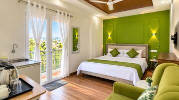 Habitación de hotel con cama, escritorio con hervidor, silla, mesita y vistas a zonas verdes.