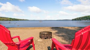 Näkymä järvelle, jossa on nuotiopaikka ja punaiset tuolit, jotka on asetettu järven suuntaan.