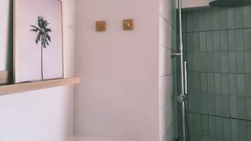 Un baño con ducha, un cuadro en la pared y un respiradero.
