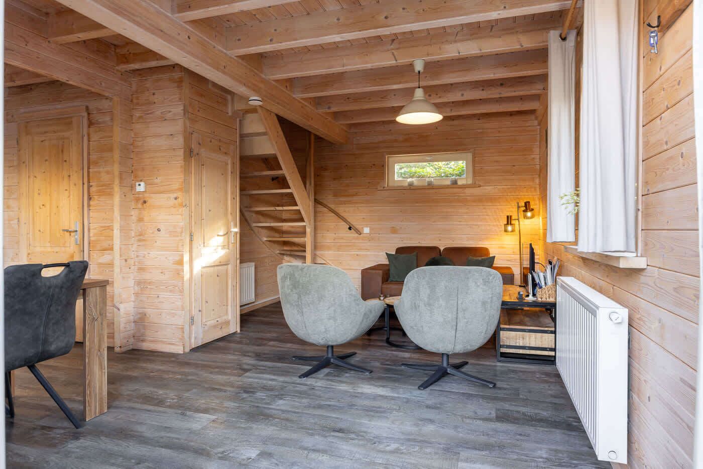 Een houten interieur met een trap, een bank en een tafel.
