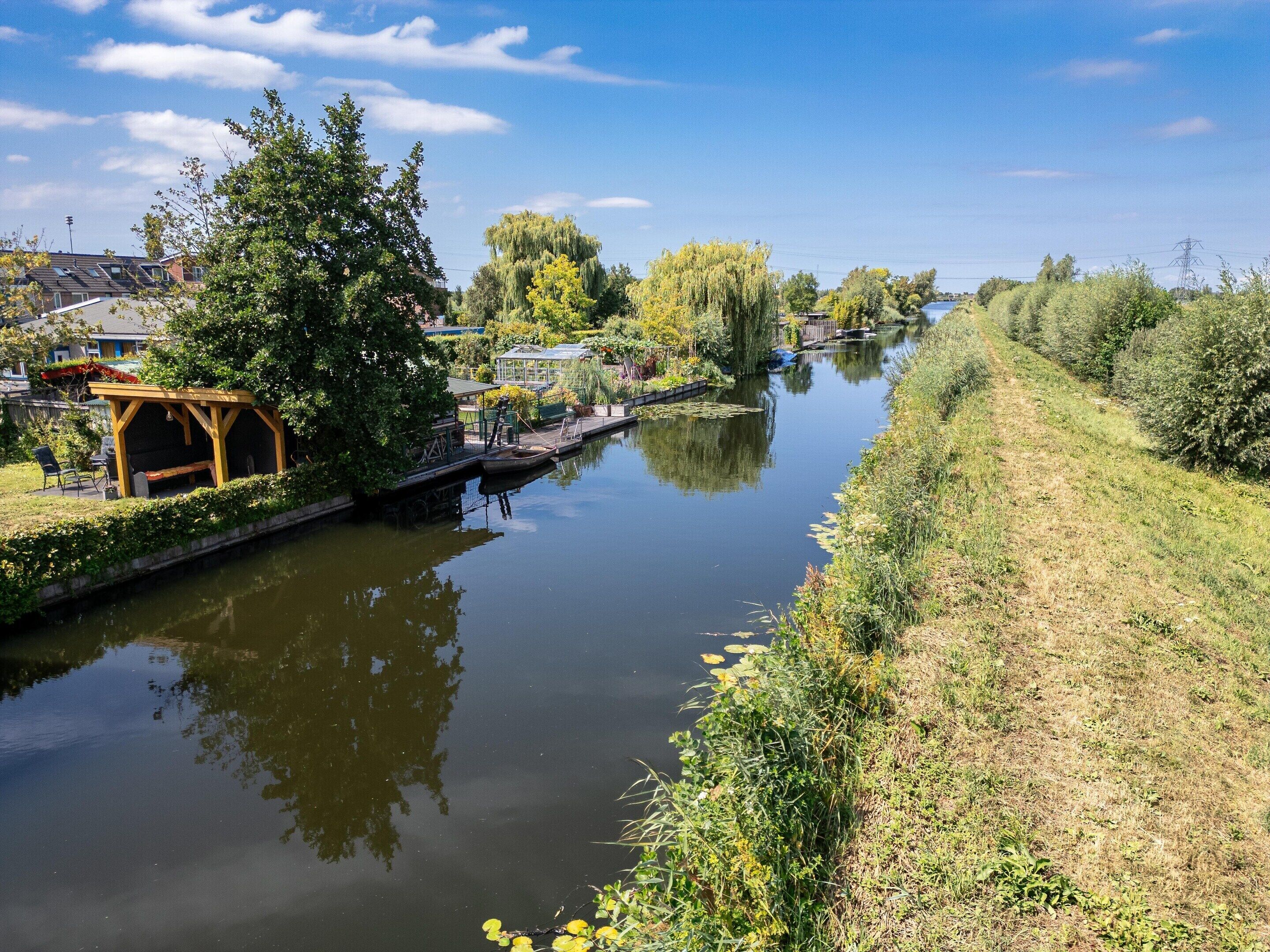Un río tranquilo con una estructura de madera a la izquierda y una orilla cubierta de hierba a la derecha.