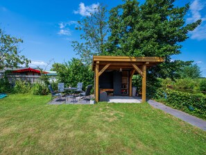 A wooden gazebo with a table and chairs, surrounded by a grassy area and trees. - Waterfront Villa With Picturesque Views (Hekendorp)