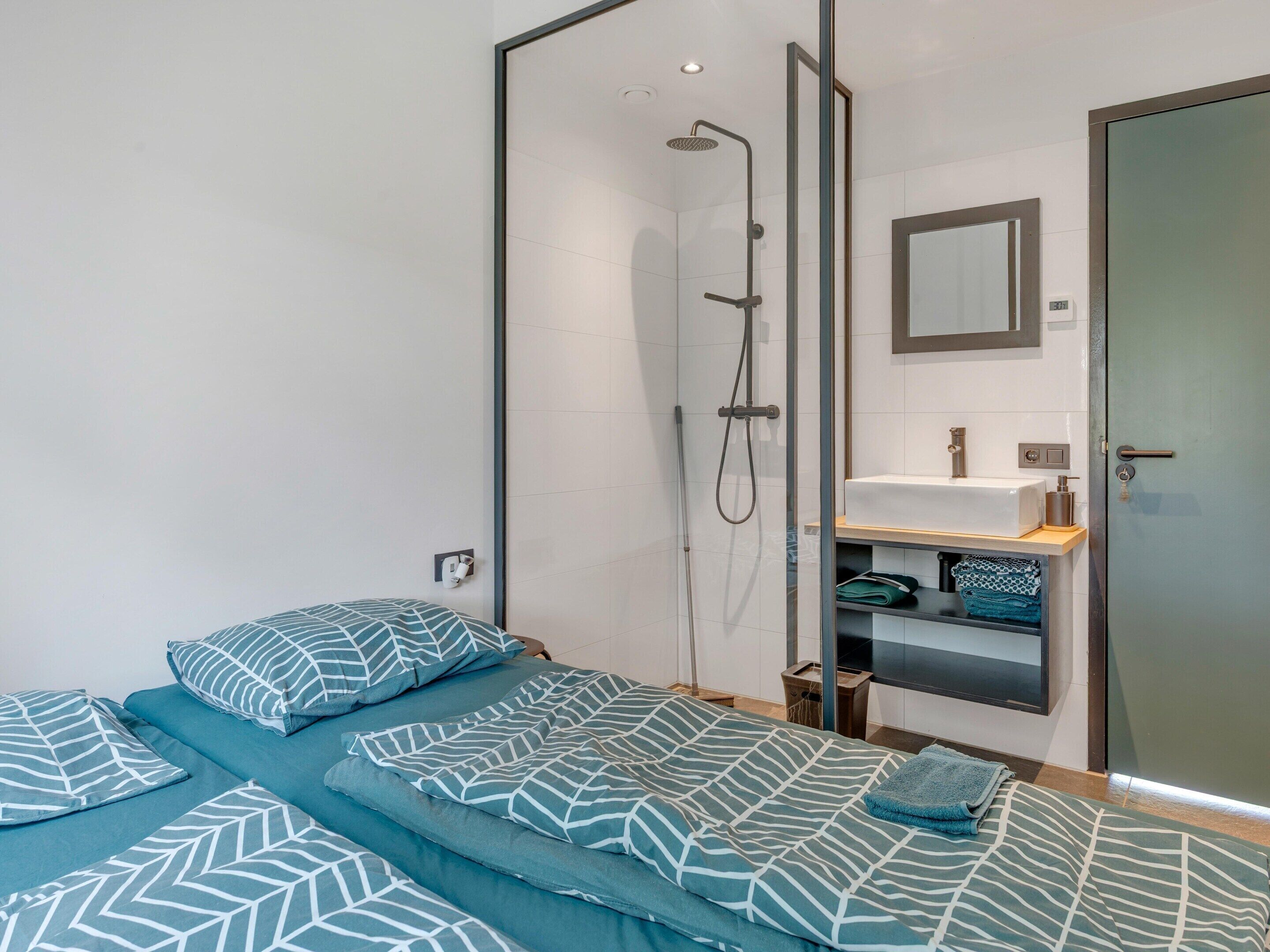 A modern bedroom with a shower, a sink, and a mirror.