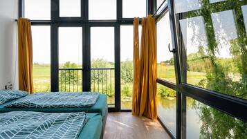 Ein Zimmer mit zwei Betten, großen Fenstern und Blick auf eine grüne Landschaft.