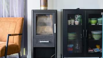 Een moderne keuken met een ingebouwde kookplaat, een kast met servies en een stoel.