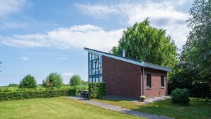 Un bâtiment moderne à la façade vitrée, entouré d’une pelouse bien entretenue et d’arbres majestueux.