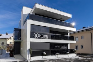 A modern two-story apartment building with a prominent 'B HOME APARTMENT' sign. - Penthouse with a dream view (Bramberg am Wildkogel)