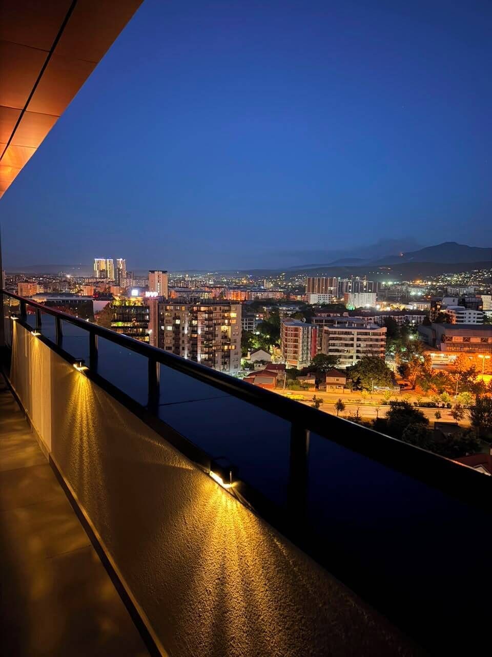 A nighttime cityscape with buildings and a body of water.