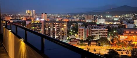 A nighttime cityscape with buildings and a body of water.