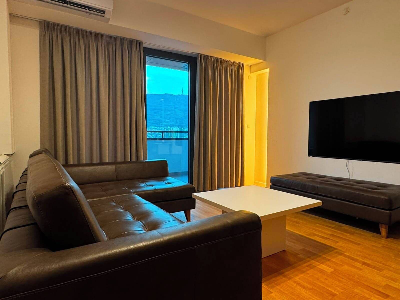 Una sala de estar moderna con un sofá, una mesa de centro y un televisor de pantalla plana.