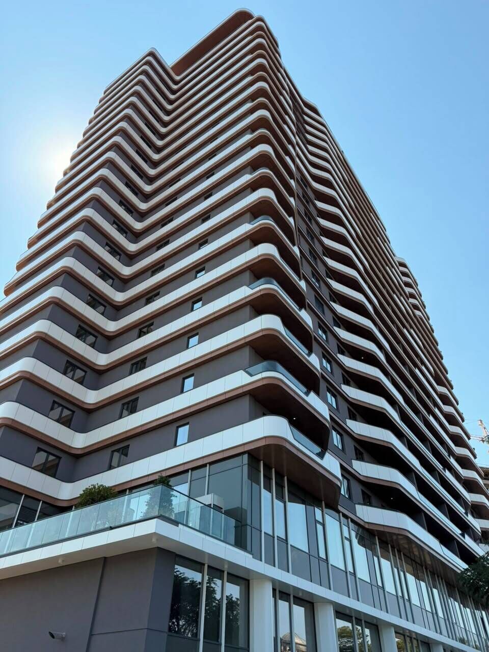 Un edificio de gran altura con un diseño arquitectónico en zigzag, que cuenta con varios balcones y grandes ventanales.