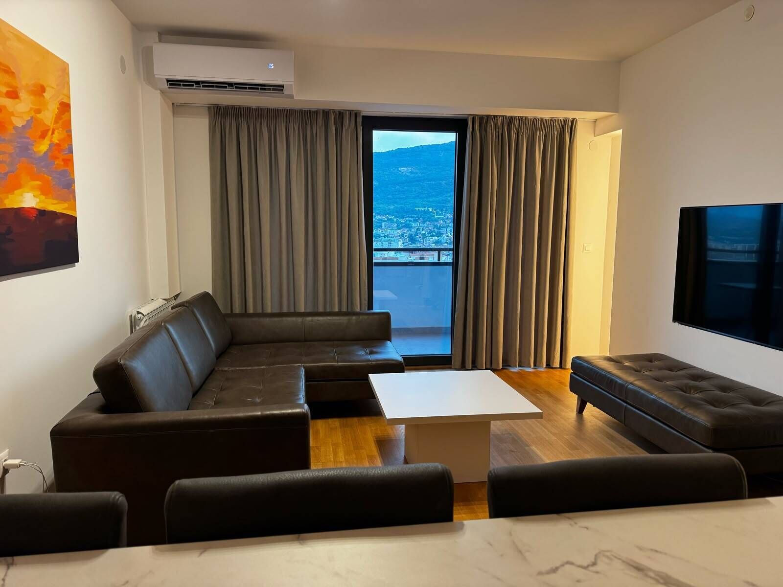 A modern living room with a sectional sofa, a coffee table, and a flat-screen TV.