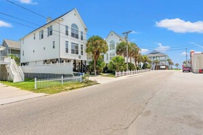 A street view with a two-story white building, a sidewalk, a fence, and a parked vehicle. - Sunshine Daydream - Close to Beach/Shared Pool (North Myrtle Beach)
